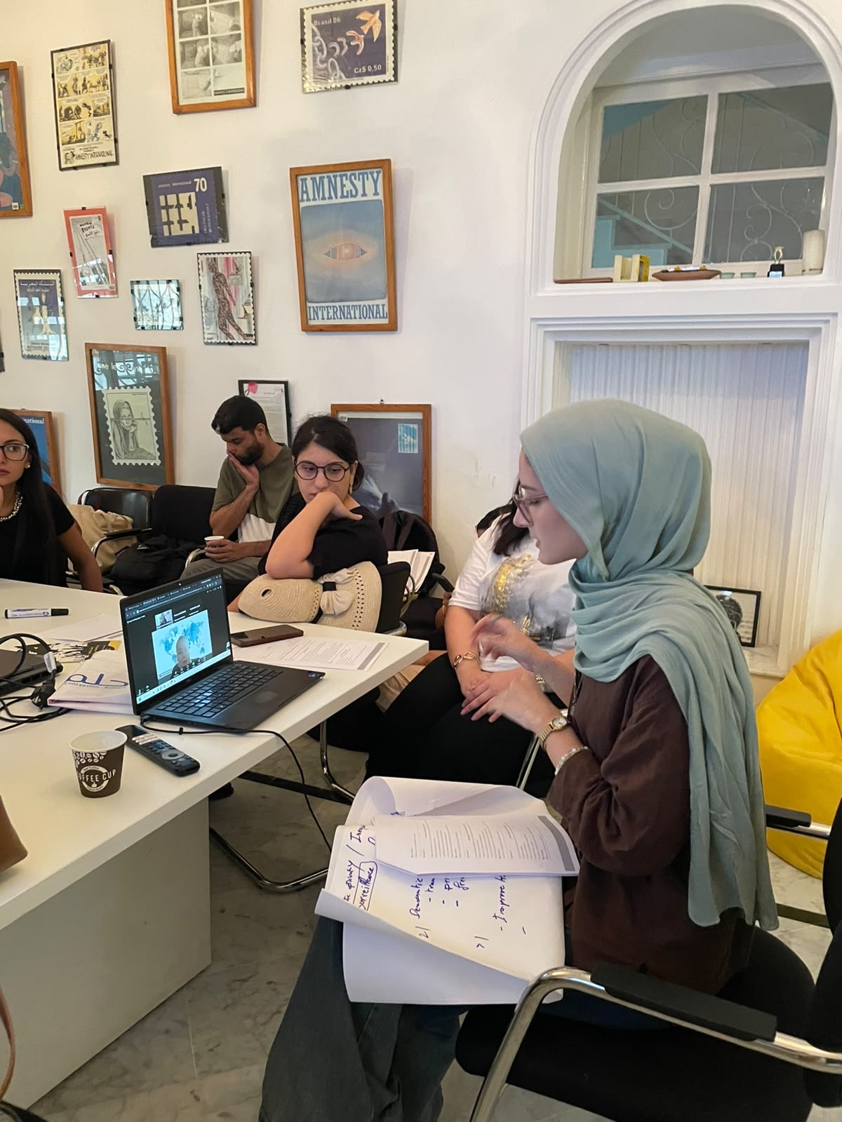 A small group works through a practical AI governance case, following a remote session and comparing notes on privacy and surveillance