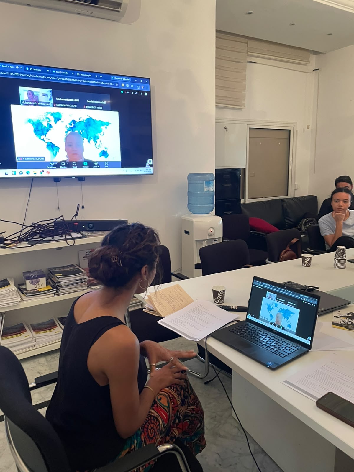 Participants follow Ermelinda Kanushi's remote introduction to AI governance, joining live over video